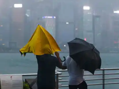 Menschen mit Regenschirmen k&auml;mpfen in Hongkong mit starkem Wind und Regen des Taifuns &laquo;Saola&raquo;.