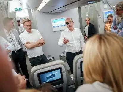 Bundeskanzler Olaf Scholz (r, SPD) und Finanzminister Christian Lindner (FDP) sprechen auf dem Flug nach Neu Dehli mit Journalisten.