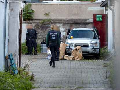 Polizistinnen und Polizisten stehen in einem Hinterhof in der Duisburger Innenstadt, auf dem Boden stehen Papiert&uuml;ten mit Beweismitteln.