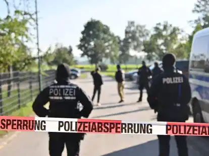Einsatzkr&auml;fte der Polizei stehen hinter einer Polizeiabsperrung nach einer Razzia in Hesselbronn.