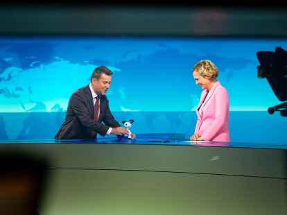 Jens Riewa (l-r) schenkt Caren Miosga am Ende ihrer letzten Sendung eine Snoopy-Figur (Jonas Walzberg/dpa)