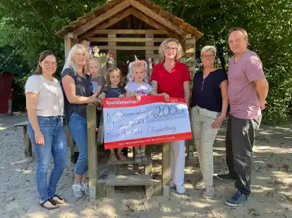 Den symbolischen Spendenscheck hat Filialleiterin Marita L&uuml;bbers (sechste von links) an den Vorstand um Jasmin Schr&ouml;er (von links), Olga Friesen, Kita-Einrichtungsleiterin Silvia Oberschelp und Ingo Busch &uuml;berreicht.