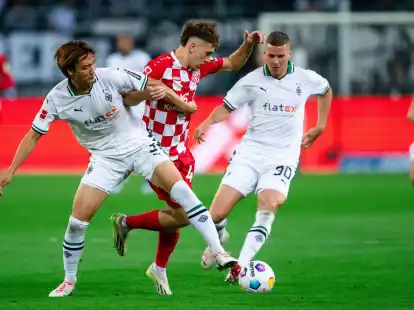 Nach einem harten Kampf trennen sich Gladbachs Ko Itakura (l) und der Mainzer Brajan Gruda (M)und ihre Teams 1:1.