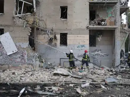 Ukrainische Feuerwehrleute l&ouml;schen ein Feuer nach einem Luftangriff, der ein Wohnhaus besch&auml;digt hat.