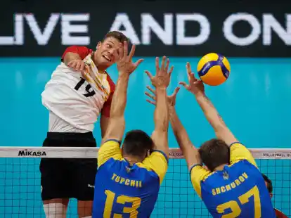 Volleyballer Erik R&ouml;hrs schmettert einen Ball am ukrainischen Block vorbei.