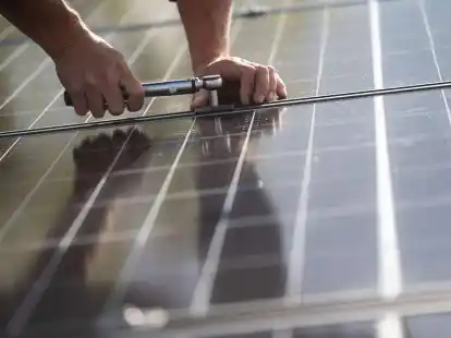 Mitarbeiter einer Firma montieren Photovoltaikmodule auf dem Dach eines Wohnhauses.