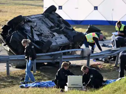 Rettungskr&auml;fte und Polizisten am umgest&uuml;rzten Fahrzeug. Beim Unfall sind sieben Menschen gestorben und mehrere schwer verletzt worden.