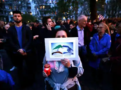 Menschen nehmen vor der Synagoge am Berliner Fraenkelufer an einer Mahnwache teil.