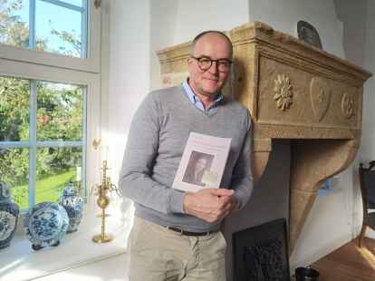 Kai Nilson mit dem Buch von Gabriele L&uuml;bke &ndash; hier in seiner K&uuml;che wird die Lesung stattfinden.