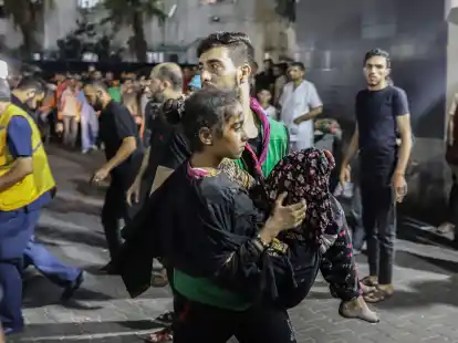 Ein Mann tr&auml;gt nach dem Raketeneinschlag ein verletztes M&auml;dchen.