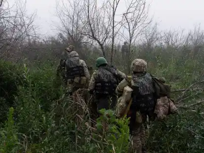 Ukrainische Marinesoldaten gehen durch Gel&auml;nde an der Frontlinie in Cherson.