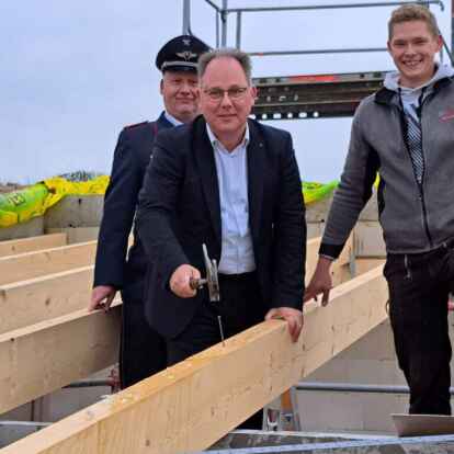 Der Nagel sitzt. Samtgemeinde Harald Hinrichs schwingt den Hammer unter den Augen von Ortsbrandmeister Stefan Bender und Alexander Wilken von der Firma ABV. Zahlreiche G&auml;ste waren bei der Zeremonie mit dabei