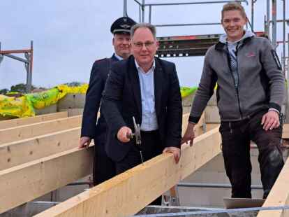 Der Nagel sitzt. Samtgemeinde Harald Hinrichs schwingt den Hammer unter den Augen von Ortsbrandmeister Stefan Bender und Alexander Wilken von der Firma ABV. Zahlreiche G&auml;ste waren bei der Zeremonie mit dabei