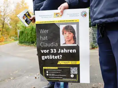 Ein Polizist mit einem Plakat zum Mordfall von 1990 in R&ouml;thenbach an der Pegnitz.