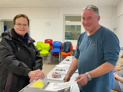 Monika Urban, hier mit Reinhard Behrends (stellvertretender Wahlleiter Bezirk 101), steckt ihren Stimmzettel in die Urne in der Grundschule Heidem&uuml;hle.