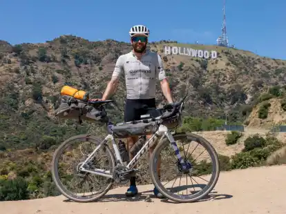 Der deutsche Athlet Jonas Deichmann mit seinem Fahrrad vor der Kulisse der Hollywood Hills in den USA.