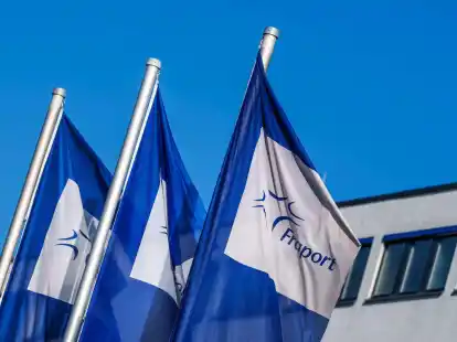 Flaggen mit dem Logo der Fraport AG wehen vor der Firmenzentrale im Wind.