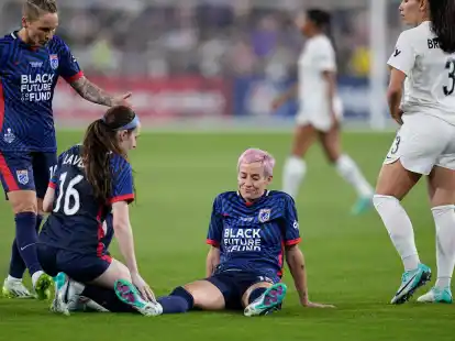 Megan Rapinoe (M) bleibt nach einer Verletzung auf dem Rasen liegen.