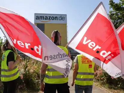 Streikende stehen mit Verdi-Flaggen vor einem Verteilzentrum des Online-H&auml;ndlers Amazon in Leipzig (Archivbild).