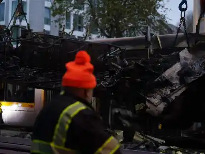 Spuren der Ausschreitungen in Dublin. Ein Arbeiter steht vor einer ausgebrannten Stra&szlig;enbahn.