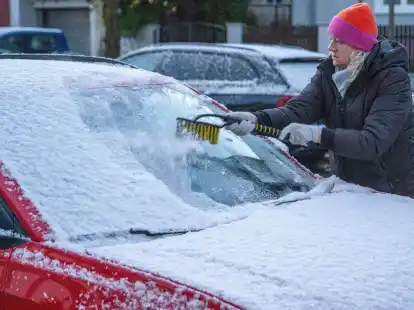 Eine Frau in M&uuml;nchen befreit am fr&uuml;hen Morgen ein Auto von Schnee und Eis. Auch in den kommenden Tagen soll es winterlich bleiben.