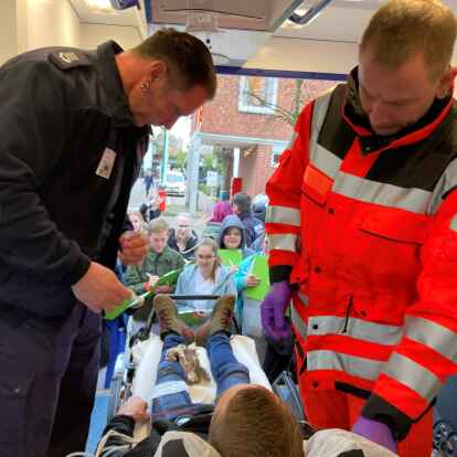 Vor dem Rettungswagen stehen die Auszubildenden und schauen den Einsatzkr&auml;ften auf die Finger: Bei der &bdquo;Spusi&ldquo; im Oldenburger Klinikum wurde einen Tag lang ganz viel falsch gemacht &ndash; und die Auszubildenden mussten sich auf Fehlersuche machen.