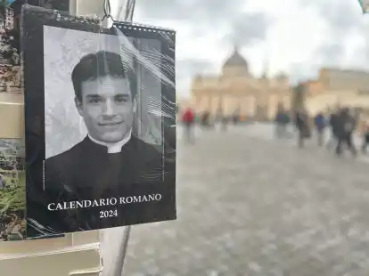Der &laquo;Calendario Romano&raquo; an einem Souvenirstand, im Hintergrund der Petersdom.