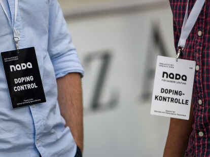 Bitten zur Doping-Kontrolle: Zwei M&auml;nner tragen Umh&auml;nger mit der Aufschrift &bdquo;Nada Doping Control" und &bdquo;Nada Dopingkontrolle" bei einem Spiel der Fu&szlig;ball-Bundesliga. 