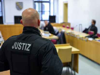 Ein Justizbeamter steht vor Prozessbeginn vor einigen Angeklagten im Landgericht Chemnitz.