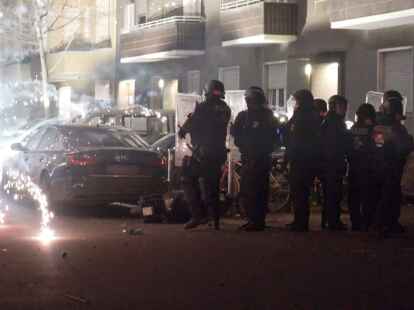 Polizisten stehen in der Silvesternacht 2022 hinter explodierendem Feuerwerk in&nbsp;Berlin.