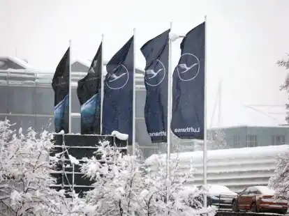Fahnen der Lufthansa wehen am  Flughafen M&uuml;nchen im Schneetreiben. Die deutsche Fluggesellschaft kauft neue Maschinen ein.