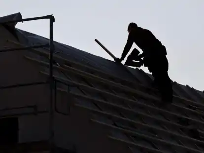 Ein Dachdecker arbeitet auf einem Einfamilienhaus am Stadtrand von Leipzig (Symbolbild).
