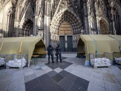 Polizisten mit Maschinenpistolen stehen vor dem K&ouml;lner Dom. Nach dem Terroralarm f&uuml;r das Gotteshaus sind drei weitere Verd&auml;chtige festgesetzt worden.