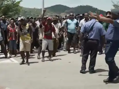 Das Videostandbild zeigt zwei Polizisten neben einer aufgebrachten Menschenmenge in Port Moresby.