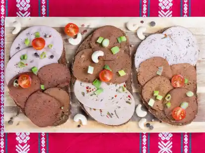 Brotscheiben belegt mit verschiedener veganer Wurst liegen auf einem Holzbrett (Symbolbild).
