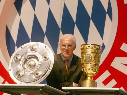 Franz Beckenbauer 2006 zwischen Meisterschale und DFB-Pokal.
