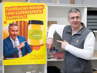 Imker Rico Heinzig neben einem Plakat mit dem Foto des Moderators Jan B&ouml;hmermann.