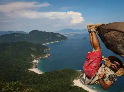 Ein Mann h&auml;ngt f&uuml;r ein Bild an dem Felsen &laquo;Pedra do Telegrafo&raquo; bei Rio de Janeiro.