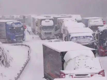 Lastwagen stecken im Stau auf der schneebedeckten Autobahn 5 bei Alsfeld fest.