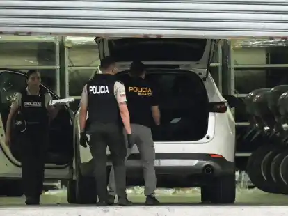 Polizisten in Schutzwesten untersuchen das Auto des erschossenen Staatsanwalts C&eacute;sar Su&aacute;rez.