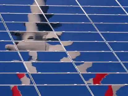 Ein Windrad spiegelt sich in einer Solar-Anlage.