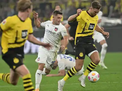 Dortmunds Niclas F&uuml;llkrug (r) und Heidenheims Nikola Dovedan (M) k&auml;mpfen um den Ball.