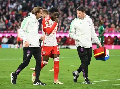 Alphonso Davies (M) wird verletzt vom Platz begleitet.