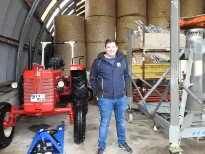 Zwischen Familienbasis und Zukunft: Jonas Toben kann seine Ger&auml;te auf dem elterlichen Hof lagern. Hier steht der junge Gr&uuml;nder zwischen dem alten Traktor und einem Kran f&uuml;r schwere Mauer-Elemente.