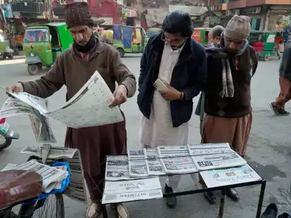 Menschen lesen an einem Stand in Lahore die Morgenzeitung. Pakistans Wahlen waren &uuml;berschattet von Internetsperren und Manipulationsvorw&uuml;rfen.