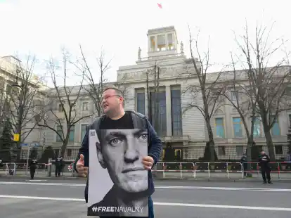 Ein Aktivist steht mit einem Plakat von Kremlkritiker Alexej Nawalny vor der russischen Botschaft in Berlin und protestiert.