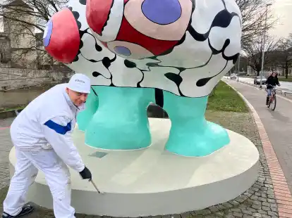 Maler Andreas Rollitz streicht den Sockel der Nana-Figur &bdquo;Caroline&ldquo; am Hohen Ufer in Hannover.