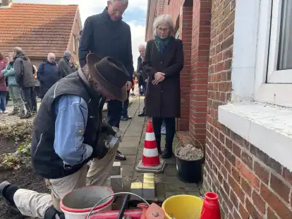 Interessiert beobachten B&uuml;rgermeister Rolf Clau&szlig;en und Christine Lammers, wie Gunter Demnig die Stolpersteine setzt.
