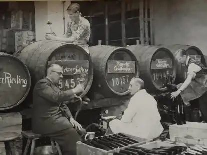 Carl Klettner (links) probiert mit seinen Mitarbeiterinnen und Mitarbeitern vom Wein, den er in F&auml;ssern von der Mosel holen lie&szlig;. Einmal ge&ouml;ffnet, musste der komplette Inhalt der F&auml;sser sofort in Flaschen abgef&uuml;llt werden, damit der Wein nicht verdarb.