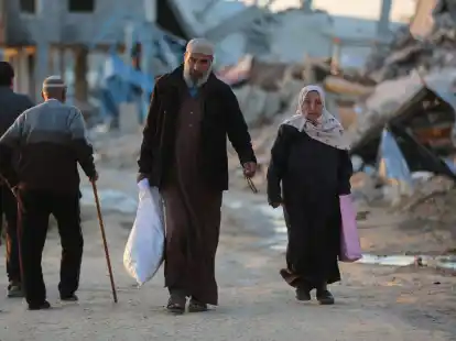 Menschen gehen an zerst&ouml;rten Geb&auml;uden im Fl&uuml;chtlingslager Al-Maghazi im Zentrum des Gazastreifens vorbei. Das Bangen um eine Feuerpause vor Ramadan geht weiter.